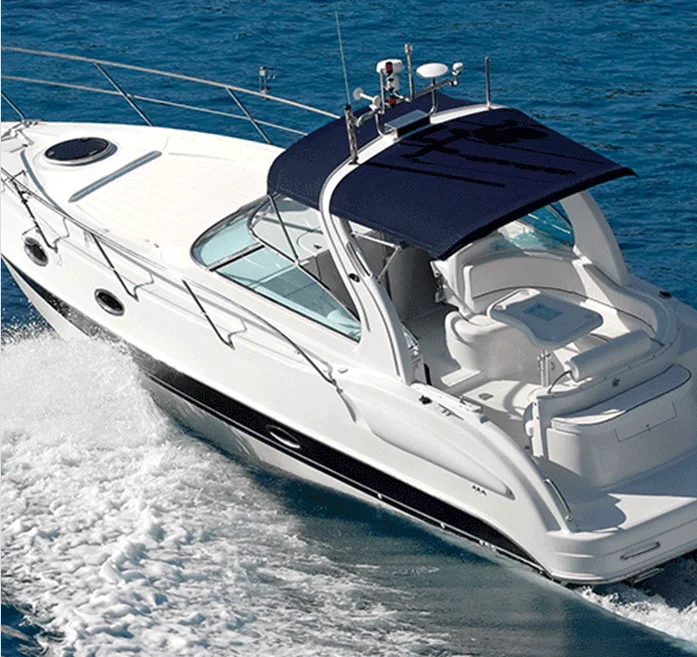 A white motor yacht with a navy blue canopy cruises quickly on clear blue water, creating a wake behind it.